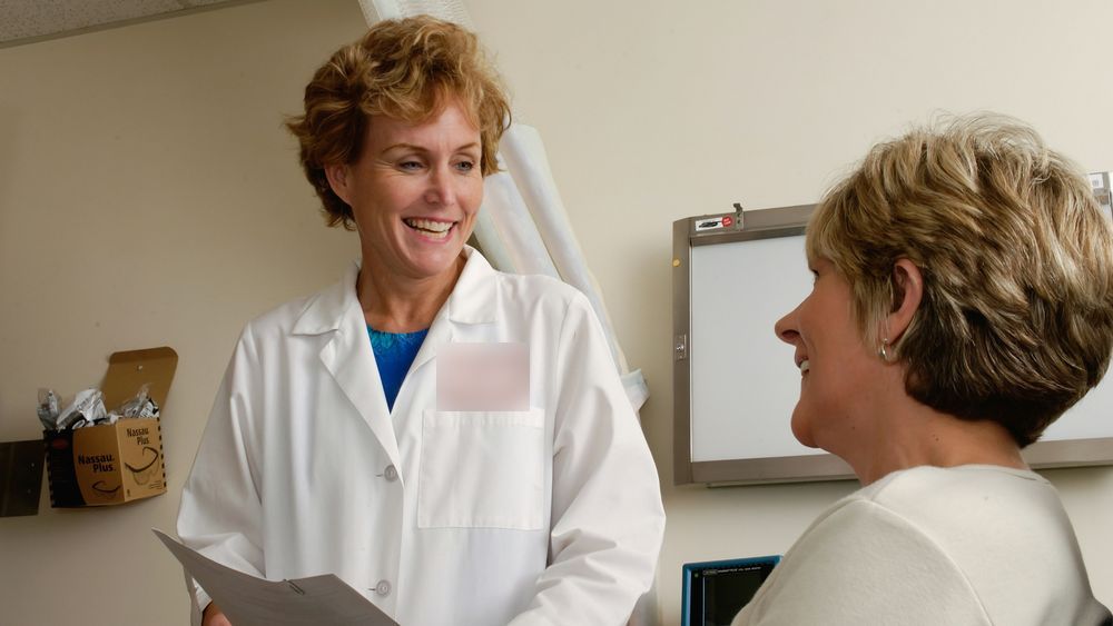 A doctor talking with a woman patient in an examination room